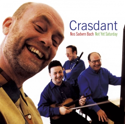 A smiling bald man fills the left foreground, with three men in blue shirts and the title “Crasdant” on a white background.